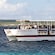 A water taxi full of people floats across a bay